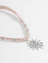 Collar de cordón de tela con estampado de cuadros vichy en tonos rosado y verde, con dije central de sol en metal dorado y detalles de cuentas metálicas a lo largo del cordón.