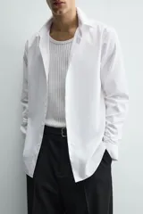Camisa de corte slim fit confeccionada en tejido de algodón con textura. Presenta cuello italiano, manga larga con puños abotonados y cierre frontal mediante botonadura.
