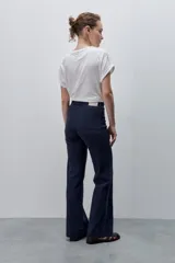 Pantalón de jean azul marino, de tiro alto y calce ajustado con pierna recta levemente amplia, bolsillos traseros y recortes verticales en el delantero.