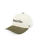 Gorro tipo cap con visera curva, cuerpo en color crema y visera en color verde oliva. Presenta el logo de la marca bordado en el frente y un detalle lateral con las iniciales de la marca.