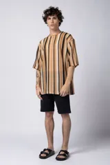 Remera de tejido tipo crochet con diseño de rayas verticales en tonos tierra, beige y negro. Presenta un corte oversize con mangas cortas y cuello redondo.