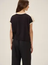 Remera negra de punto fino, con mangas cortas, cuello redondo y corte relajado. Cuenta con costuras verticales decorativas en el frente.