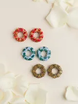 Aros de porcelana modelada a mano en forma de argolla decorada con apliques de flores, con perno de acero quirúrgico.