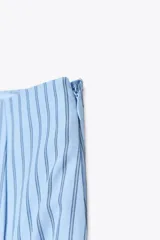 Falda midi celeste con rayas verticales finas en azul marino, de tiro alto, con pliegues en el delantero y cierre lateral con cremallera oculta.