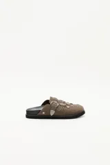 Zueco de cuero descarne negro con diseño de estilo western, decorado con tachas metálicas plateadas y una hebilla lateral ajustable.