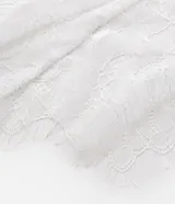 Pañuelo de cintura femenino confeccionado en encaje blanco con diseño floral, con amarre lateral y terminación irregular.