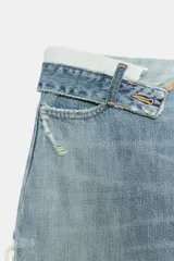 Jeans de mezclilla de tiro medio, corte wide leg y diseño relaxed. Presenta detalles rotos y desgastados en las piernas, y una cinturilla doblada superpuesta con trabillas y cierre frontal con cremallera y botón metálico.