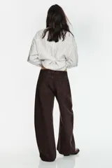 Camisa de corte oversize con estampado de rayas verticales, cuello solapa, cierre frontal con botones y mangas largas con puños abotonados.