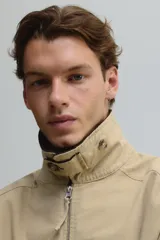 Campera tipo blouson de algodón color beige claro, con cuello de pana marrón oscuro. Posee cierre frontal, bolsillos delanteros ribeteados y elástico ajustable con cordón en el bajo.