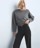 Jeans negros de tiro medio a bajo, corte recto y holgado, con diseño clásico de cinco bolsillos y cierre frontal con botón y cremallera.