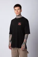 Remera negra de algodón de corte oversize, con mangas cortas y cuello redondo. Estampado pequeño en el frente y diseño grande en la espalda con Mickey Mouse y caracteres orientales en tonos rojizos.