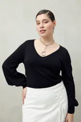 Top negro de tejido sutilmente metalizado, con escote en V y mangas abullonadas.