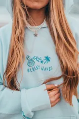 Hoodie celeste con capucha, puños y ruedo acanalados. Presenta un bordado en el pecho con motivos playeros y la frase "Glassy Waves".