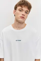 Remera blanca de manga corta, corte oversize, con estampa en la espalda de una flor sobre fondo difuminado verde y blanco.