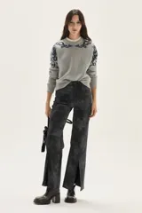 Sweater de tejido de punto color beige con diseño de arabescos en tonos marrones en hombros y mangas. Presenta cuello redondo con cordones decorativos y puños con textura acanalada.