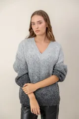 Sweater de punto con escote en V, diseño de mangas largas y efecto degradado que transiciona de un tono crema en la parte superior a un tono beige en la parte inferior.