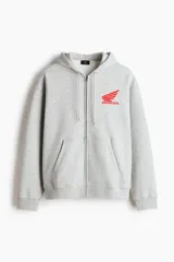 Campera con capucha gris melange de felpa con interior cepillado, cierre frontal, hombros caídos y bolsillos tipo canguro. Presenta estampado pequeño de Honda en el pecho.