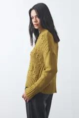 Polera de tejido de punto color marrón, con cuello alto y diseño de textura con relieves y trenzas. Posee mangas largas con puños acanalados.