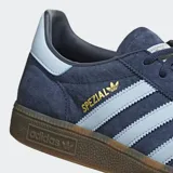 Championes Adidas Handball Spezial, color azul marino con detalles en celeste y suela marrón. Confeccionados en gamuza con las tres tiras clásicas de Adidas en los laterales y el nombre del modelo en dorado.