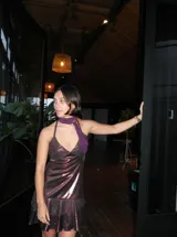 Vestido corto de tela metalizada en tono fucsia con reflejos dorados, con escote en V, diseño de top con triángulos, aberturas laterales en la cintura y doble volado irregular en el ruedo.