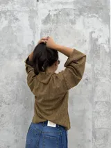 Polera de tejido de punto acanalado en color ocre, con cuello alto y diseño de mangas amplias. Presenta un corte recto y holgado con un detalle de cuello abierto lateral.