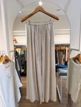 Pantalón amplio color beige, confeccionado en mezcla de tencel y lino, con cintura elástica, lazo regulable y botones frontales decorativos.