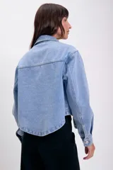 Sobrecamisa de jean azul con bolsillos frontales con solapa, cuello clásico y cierre de botones metálicos.