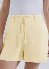 Short de lino en color crudo, de corte recto y tiro medio. Presenta una cintura con pasacintos y un cordón trenzado decorativo con borlas en el frente.