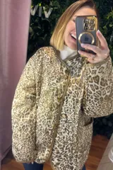 Campera acolchada de corte recto con estampado animal print en tonos neutros. Presenta cierre frontal con botones, cuello redondo y ribetes en color contrastante.