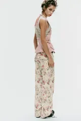 Jeans rectos de tiro medio con estampado floral multicolor sobre base blanca, trabillas para cinto, bolsillos delanteros y cierre frontal con cremallera y botón metálico.