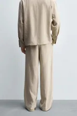 Pantalón de corte relaxed fit confeccionado en una mezcla de lyocell y lino. Presenta bolsillos frontales, bolsillos traseros de vivo y cierre frontal con cremallera y botón.