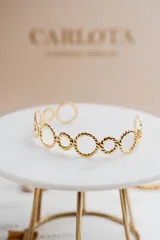 Pulsera dorada de acero quirúrgico con baño de oro 18k, formada por círculos texturizados entrelazados.