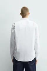 Camisa de corte slim fit confeccionada en tejido de algodón, con cuello italiano, manga larga con puños abotonados y cierre frontal de botones.