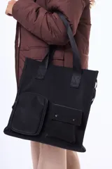 Bolso tipo tote negro de diseño estructurado, con doble asa superior y correa ajustable. Presenta dos bolsillos frontales funcionales, uno con cierre y otro con solapa y broches a presión.