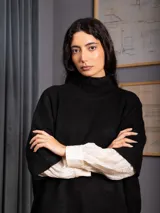 Polerón negro de tejido de punto con cuello alto, diseño oversized, mangas 3/4 y corte asimétrico más largo en la parte posterior.