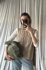 Cartera tipo hobo de tela color verde oliva, con diseño holgado, cierre superior y parche de cuero sintético con logo en el frente.