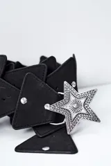 Cinto negro de diseño ancho con múltiples piezas superpuestas y una gran hebilla metálica plateada en forma de estrella con grabados texturizados.
