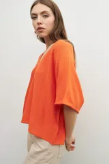 Sweater naranja de tejido de punto, corte oversized y escote en V.