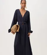 Vestido largo midi estilo chemise de color azul marino, confeccionado en mezcla de viscosa y lino. Presenta escote en V, mangas largas con puños abotonados, cierre frontal de botones y cinturón ajustado del mismo tejido con hebilla redondeada.
