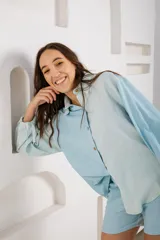 Camisa blanca con estampado de hojas en tonos beige y verde, cuello camisero, mangas largas con lazos en los puños y botones de madera.