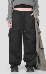 Pantalón cargo de corte regular confeccionado en textil técnico pesado. Presenta cintura elástica con cordón de ajuste, bolsillos laterales en la cintura y bolsillos cargo de gran tamaño en los muslos. Incluye elásticos con tancas en los tobillos para regular la apertura de la pierna.