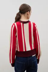 Buzo tipo polo de punto de algodón con diseño de rayas verticales en blanco y gris oscuro. Presenta cuello camisero negro, cierre frontal con botones y puños negros en las mangas y en el ruedo.