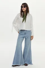 Camisa blanca de manga larga con flecos en la espalda y las mangas, confeccionada en mezcla de algodón, poliamida y elastano.