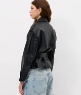 Campera de cuero sintético estilo trench, con cuello solapa, cierre frontal de botones y lazo ajustable en la cintura. Presenta detalles utilitarios en hombros y puños.