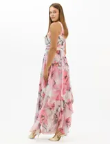Vestido largo de fiesta con estampado floral en tonos rosa y gris sobre fondo blanco. Presenta cuello halter con abertura tipo lágrima, cintura drapeada y falda amplia con capas asimétricas y bajo en picos. Confeccionado en tejido ligero con forro interior.