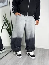 Jeans baggy de corte amplio y tiro medio, con diseño degradado en tonos gris y negro, decorado con pequeños apliques brillantes estilo strass en toda la prenda.