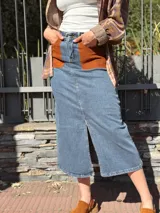 Falda midi de denim con elastano, corte recto y tajo frontal. Presenta bolsillos delanteros de cuero en color tostado y diseño clásico.