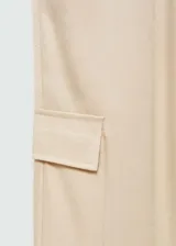 Pantalon de corte recto y diseño fluido, confeccionado en tejido satinado color beige. Cuenta con cintura elástica, bolsillos laterales, bolsillos cargo en las piernas y bolsillos de ribete en la parte posterior.