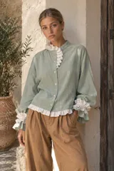 Blusa de manga larga color verde menta con volados blancos contrastantes en el cuello mao, la botonera frontal y los puños elásticos.