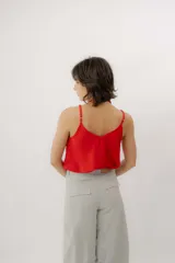 Musculosa negra con escote en V, breteles finos regulables y doble volado frontal con pespuntes.